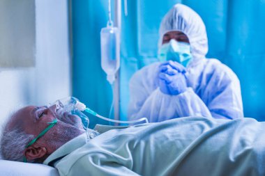 Endişeli aile üyesi ya da PPE 'li doktor ya da koruyucu giysi giyen koronavirüs ya da hasta solunum maskesi takıp hastaların solunum maskesi takıp hastanede iyileşmesi için Coperavid 19' a dua eden hasta.