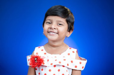 Mavi arka planda kameraya bakan sevimli mutlu Hintli çocuk portresi