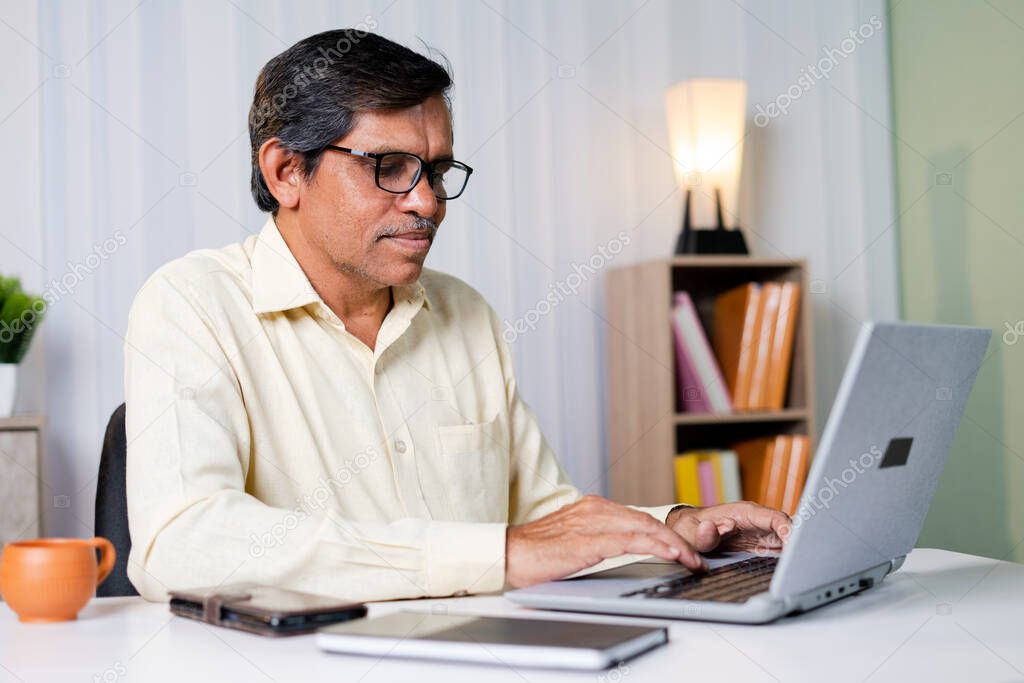 Businessman smiling while working or chatting on laptop at office - concept of using technology, communication and internet