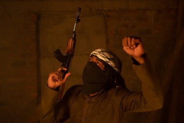 Mutlu İslami militan ya da yüzü örtülü asker savaş zaferi için elinde silahla dans ediyor..