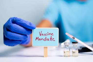 Coronavirus ya da covid-19 aşısı konsepti, aşı aşıları ve şırıngaların yanına pano yerleştirerek doktor elleriyle eldivenleri göstermek.