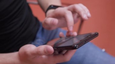 Akıllı telefonunu parşömen haberlerini kaydırmak için kullanan bir adam. Ekrana vuruyor. Ekran bulanık. Parmağına odaklan. Yakın plan.