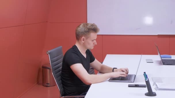 坐在办公室的办公桌前 在笔记本电脑上工作的年轻人 专心工作 提高生产力 — 图库视频影像