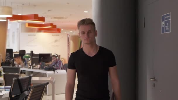 若いヨーロッパの男は夜遅くに空のオフィスを通って歩き スタートアップビジネスを経営する — ストック動画