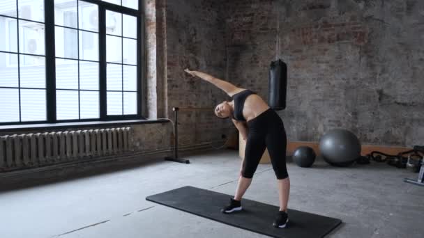 一个穿着黑色上衣和腿的年轻印度女人在健身房里做伸展运动 — 图库视频影像