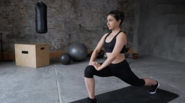 Sportif genç bir kadın yan hamle eğitiminde kalça kasları için çömelme hareketi yapıyor. Sporcu fit kız spor salonunda popo için aerobik egzersizleri yapıyor. Spor ve sağlık konsepti.