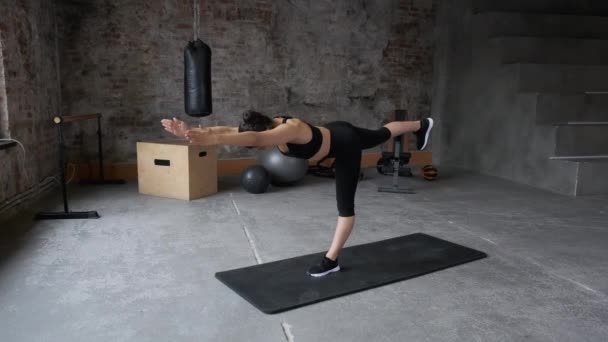 年轻的印度女子晨练平衡运动和伸展运动瑜伽 黑色运动服腿和上衣 明亮的健身房 — 图库视频影像