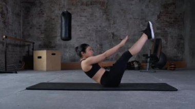 Spor giyimli atletik kız abdominalleri pompalıyor. Formda olan kadın spor salonunda, yan görüş alanında karın kası egzersizi yapıyor. Spor ve spor. Eğitim, egzersiz ve sağlık konsepti