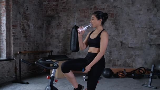 Young Athletic Indian Asian Woman Sitting Bicycle Drinking Water Bottle — Stock Video