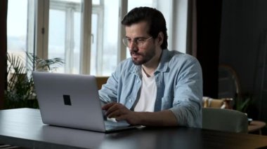 Gözlüklü Akıllı Adam, Mavi Gömlekli ve Beyaz Tişörtlü Bilgisayar Bilgisayarı 'nda çalışıyor, Evdeki Bir Masada Oturuyor Karanlık Oda' da