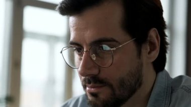 Dizüstü bilgisayarın yansımaları insanın gözlüğündeki ekranda. İnternette çalışan ve internette gezinen Kafkasyalı genç işadamının portresi. İş yerindeki hacker hesap veritabanını çalıyor.
