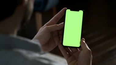 Akıllı telefon kullanan genç adam yeşil ekran izliyor cep telefonu kroma anahtar dikey yönelim görüntüleme 4k görüntülerinde eğleniyor