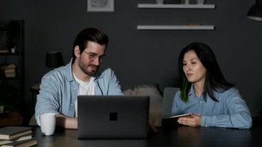 A young Man and a Woman Discuss an Online Project, Two Managers Work at Home, Use A laptop Computer