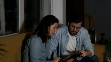 A young European Man is Talking to an Asian female Colleague Working on an Online Project, Two Managers Are working from Home, Using a Tablet