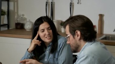 Close-Up of a Young European Man Talking to an Asian female Colleague Working on an Online Project, Two Managers Working at Home, Using a Tablet in the evening