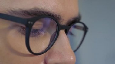 Odaklanmış iş adamının yakın görüntüsü, internet, okuma, izleme ve çevrimiçi çalışma kullanarak bilgisayar ekranına bakarak göz yorgunluğunu azaltmak için bilgisayar gözlüğü takıyor.