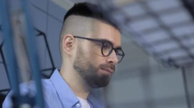 Gözlüklü, dizüstü bilgisayara bakan, evde uzaktan çalışan konsantre genç bir adam.. 