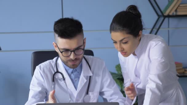 白种人年轻专业男医生与在医院实验室工作的女性专家讨论手提电脑上的考拉病毒疫苗浏览研究的近照 — 图库视频影像