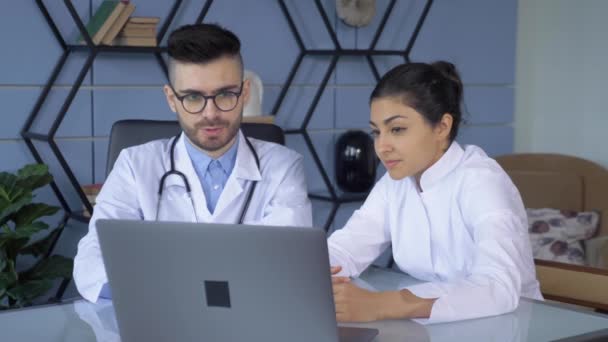 在医院明亮的办公室里有两位医生 一位是男的 一位是女的 他们在电脑或笔记本电脑上工作 — 图库视频影像