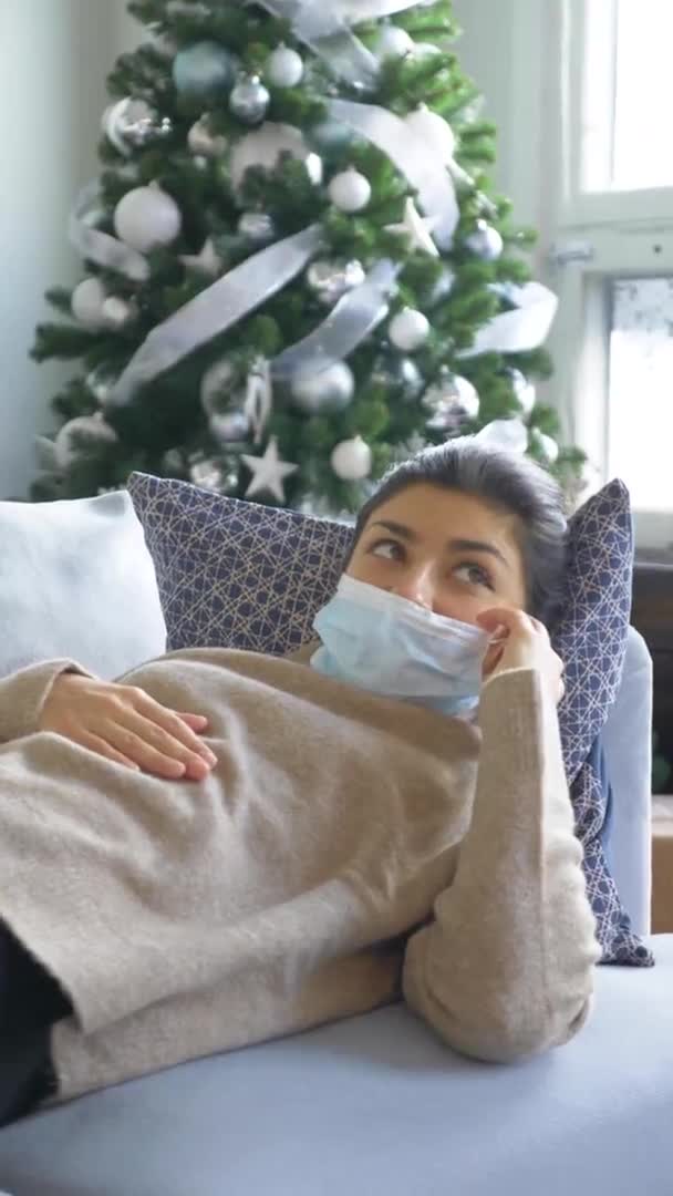 一位身穿面具的年轻生病的印度妇女 在一个舒适的房间里 躺在沙发上 在一个充满病毒传播的房间里 — 图库视频影像