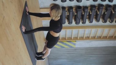 Dikey Görüntü Atletik Kadın kardiyo yapıyor bacaklarını hareket ettiriyor, spor salonunda yerde yatıyor ve vücut gücü antrenmanı yapıyor.