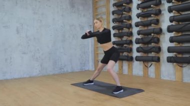 Siyah bluzlu güzel bir kız, taytlar, siyah spor ayakkabılar parlak çatı katında bacak esneme egzersizi yapıyor. Spor salonunda spor yapıyor. Sağlıklı yaşam tarzı, eğitim, spor, kilo kaybı