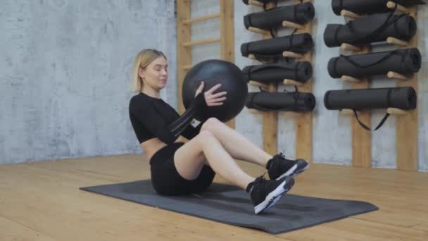 体育館でピラティスボールをして運動する若い女性 メディカルボールを使ったワークアウトをする女性アスリート — ストック動画