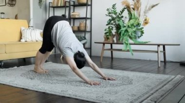 Genç sporcu kadın yoga yaparken aşağı ve yukarı doğru poz veriyor. 