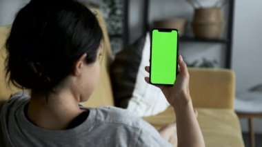 A Woman's Hand Holds A Smartphone With A Green Screen For Chromakey, Watches Social Networks, Movies, Videos, Lies on The Sofa in A Cozy Room