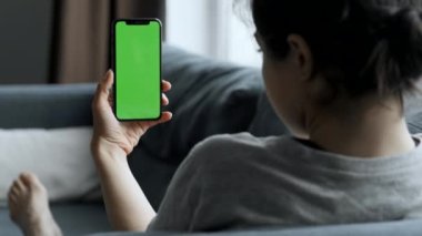 Evdeki Kadın Yeşil Model Ekranlı Akıllı Telefon kullanarak Kanepede Uzanıyor. Kız Cep Telefonu Kullanıyor, İnternet Sosyal Ağ Taraması. Görüntü Kamerası Görüntüsü.