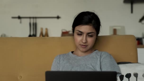 思考を失った若いインド人女性のクローズアップ肖像 ノートパソコンで働く オンライントレーニングやビジネスをする 居心地の良い部屋で自宅で仕事をする — ストック動画
