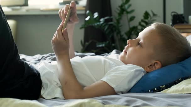 Gülümseyen Şirin Çocuk Portresi Kanepede Uzanıyor Telefondan Oynanan Bir Oyunda — Stok video