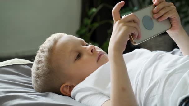 Close Portret Chłopca Patrząc Ekran Telefonu Grając Grę Smartfonie Leżąc — Wideo stockowe