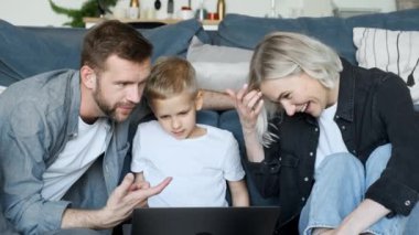 Mutlu aile hafta sonu yaşam tarzını seviyor. Modern mutfak iç mekanında rahatlıyor. Genç ebeveynler kanepeye oturuyor.