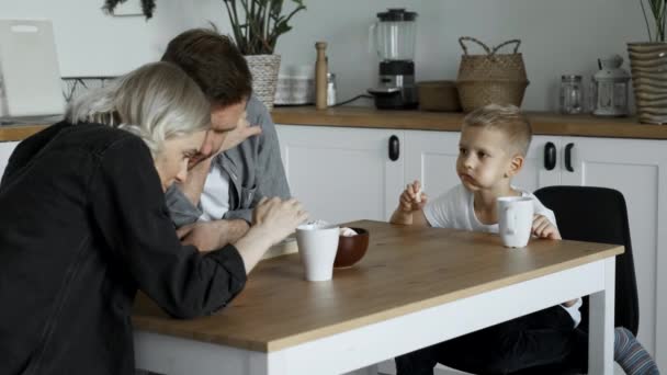 Young Family Sitting Table Kitchen Parents Looking Smartphone Screen Boy — Stok Video