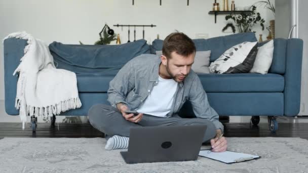 Young Man Takes Notes Paper Freelancer Works Home Uses Laptop — Stock Video