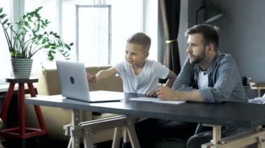 Gülümseyen oğlu evde ev ödevi yaparken yaptığı yardım için baba teşekkür