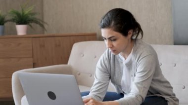 Genç Hintli Düşünceli Bir Kadın Klavyeye Yazıyor, Bilgisayarda çalışıyor, Parlak Bir Odada Bir Koltukta Oturuyor