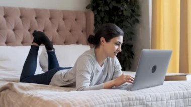 Genç Hintli Düşünceli Bir Kadın Klavyede Yazıyor, Bilgisayarda çalışıyor, Parlak Bir Odada Yatakta Yatıyor