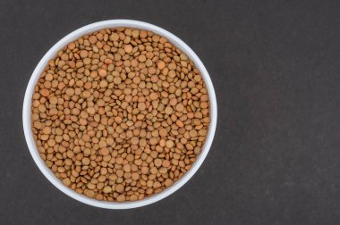 Beyaz cam bir kasede mercimek. Koyu gri arkaplanda mercimek resmi. İzole edilmiş yakın çekim fotoğrafı