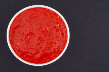 Beyaz cam bir kase ketçap. Koyu gri bir arka planda izole edilmiş. Üst görünüm kapat