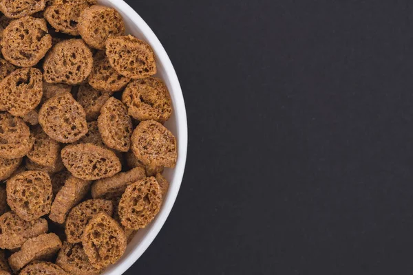 Beyaz cam kase kızarmış çavdar ekmekli bisküvi. Koyu gri bir arka planda izole edilmiş. Üst görünüm kapat