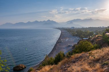 Türkiye, Akdeniz 'deki Antalya Konyaalti plajı. Arka planda güzel dağlar olan gün batımı. Üst görünüm