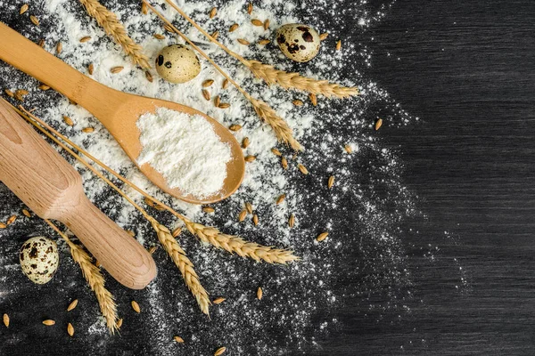 Pastane arkaplan manzarası. Yuvarlanan iğne, bıldırcın yumurtası ve kepçeyle koyu gri karatahta arka planda buğday tozu..