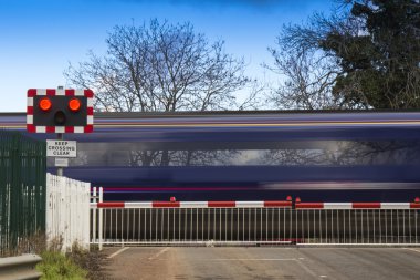 Train speeding through a level crossing clipart
