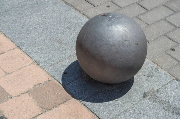 球体状の金属ブラック ボラードが隔離され通りのコンクリート床に影を落とす — ストック写真