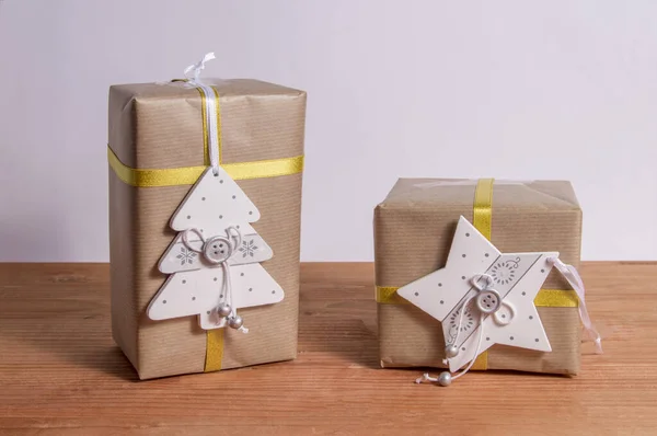 two christmas gift packages with white christmas ornaments on wooden background