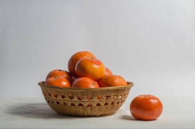 Kumaş arka planda izole edilmiş mandalinalı sepet