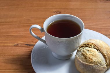 Bir fincan çay ve ahşap arka planda izole edilmiş kırsal ekmek. Yakından bakıldığında