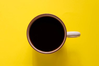 Sarı arka planda izole edilmiş bir fincan koyu kahve.